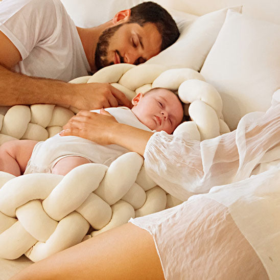 Papa dort avec bébé sur tresse de lit moelleux